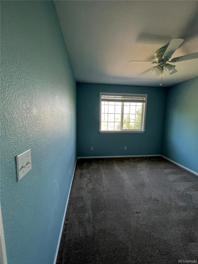 spare room with dark colored carpet and ceiling fan