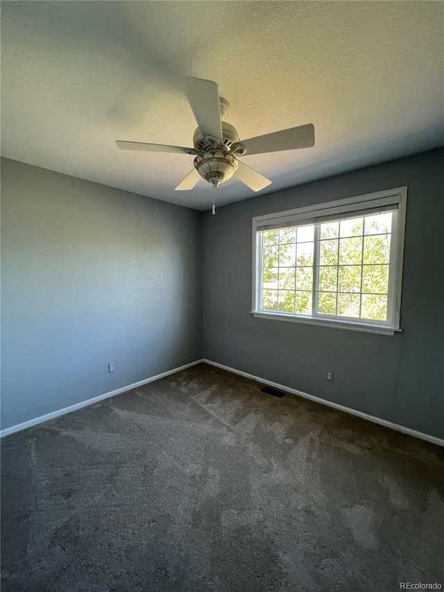 carpeted empty room with ceiling fan and a textured ceiling