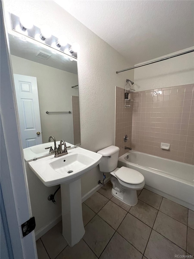 full bathroom featuring sink, tile patterned floors, a textured ceiling, toilet, and tiled shower / bath