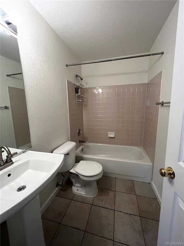 bathroom with tile patterned flooring, toilet, tiled shower / bath, and a textured ceiling