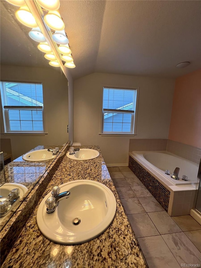 bathroom with vanity, vaulted ceiling, tile patterned flooring, a textured ceiling, and tiled bath