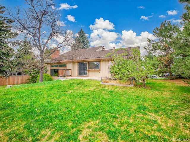 rear view of property with board and batten siding, fence, a yard, and a chimney