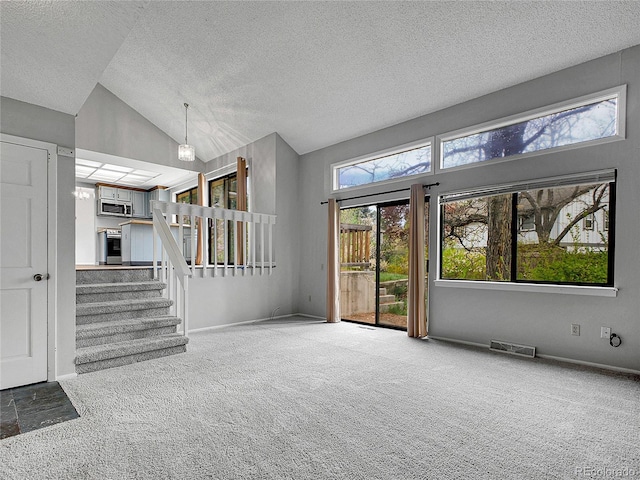 unfurnished living room with a textured ceiling, visible vents, lofted ceiling, and carpet