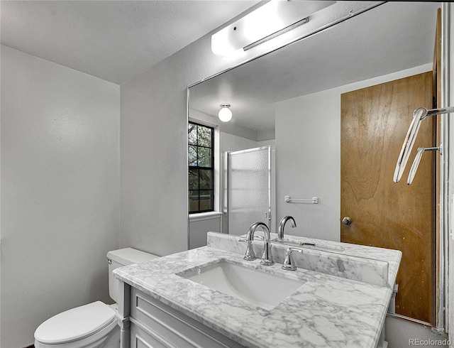 bathroom featuring vanity, a shower stall, and toilet