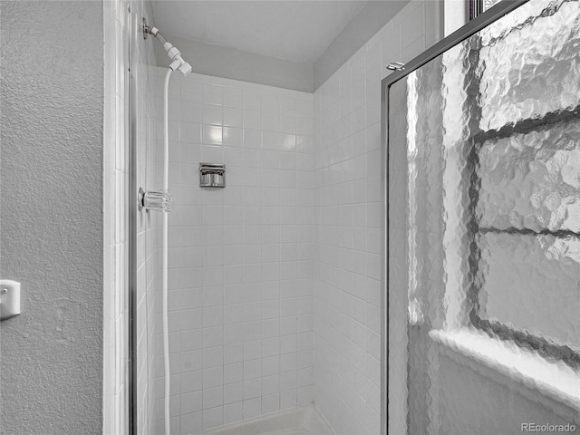 full bathroom featuring a textured wall and a shower stall