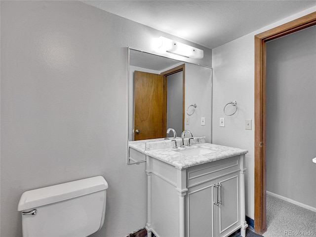 bathroom with toilet, baseboards, and vanity