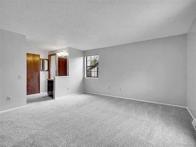 spare room featuring baseboards, carpet, and a textured ceiling
