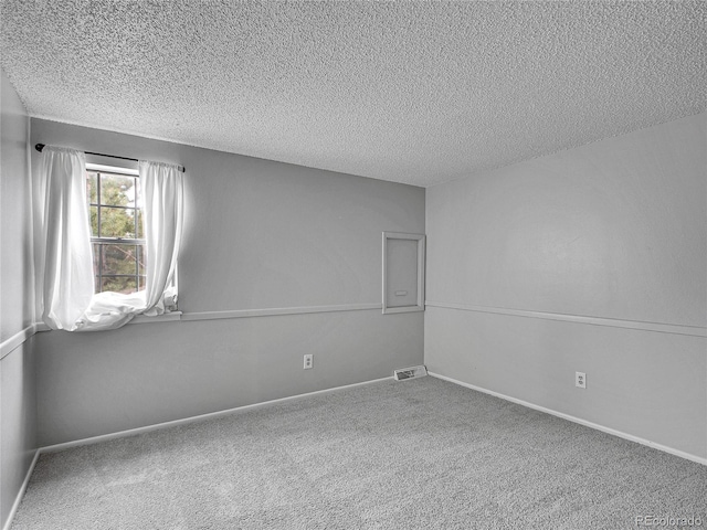 spare room with baseboards, carpet flooring, a textured ceiling, and visible vents