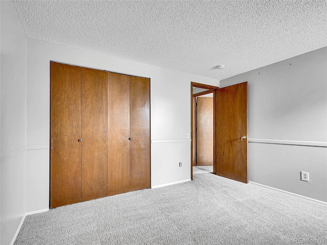 unfurnished bedroom with baseboards, a closet, carpet flooring, and a textured ceiling
