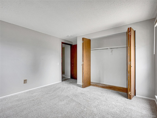 unfurnished bedroom featuring carpet flooring, a textured ceiling, baseboards, and a closet
