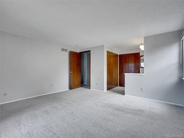 spare room featuring visible vents, a textured ceiling, carpet floors, and baseboards