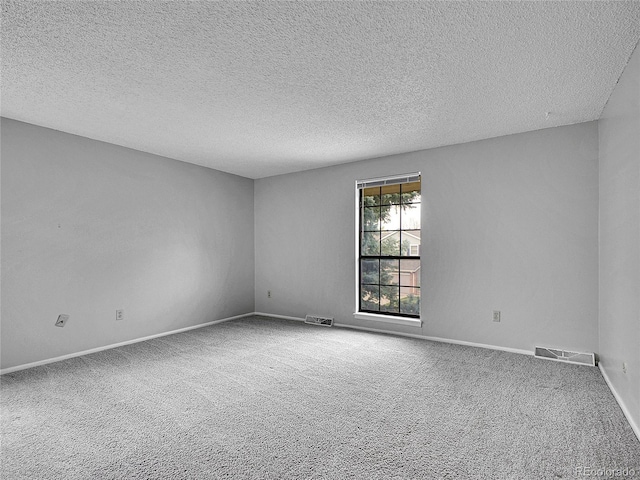 carpeted empty room featuring baseboards, a textured ceiling, and visible vents