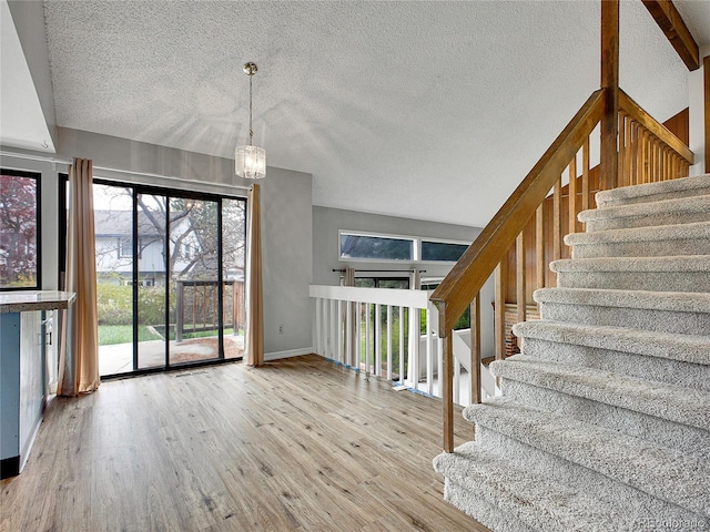interior space with baseboards, a textured ceiling, wood finished floors, and an inviting chandelier