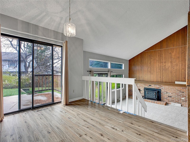 unfurnished living room featuring wood finished floors, a textured ceiling, lofted ceiling, and a wealth of natural light