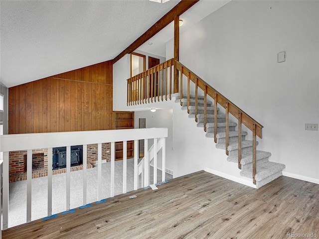 stairs featuring a textured ceiling, a fireplace, vaulted ceiling, wood finished floors, and baseboards