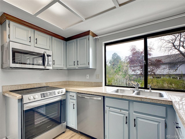 kitchen featuring light countertops, stainless steel appliances, a sink, and light wood-type flooring