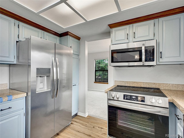 kitchen with stainless steel appliances, baseboards, tile countertops, and light wood-style floors