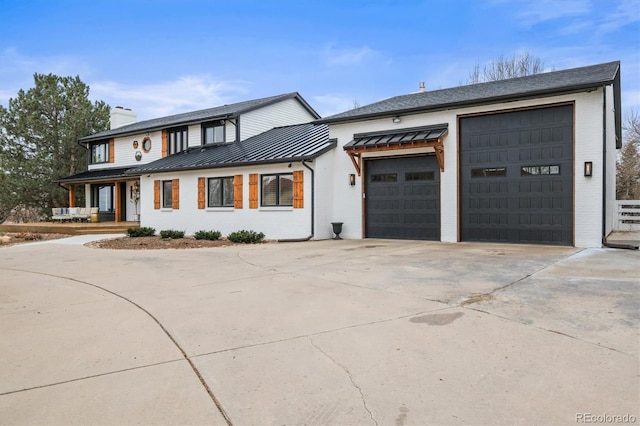 view of front of home with driveway, a standing seam roof, a garage, brick siding, and metal roof