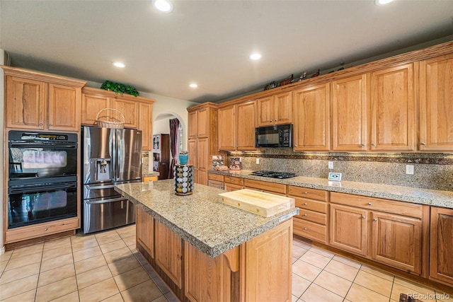 kitchen featuring arched walkways, a kitchen island, black appliances, and light tile patterned floors