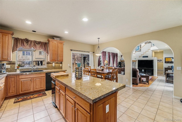 kitchen with a center island, light tile patterned floors, decorative backsplash, arched walkways, and a sink