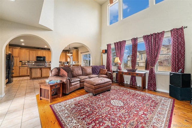 living area featuring arched walkways, a healthy amount of sunlight, and light wood finished floors