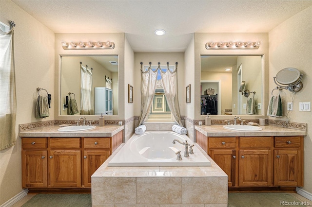 full bath with two vanities, a garden tub, and a sink