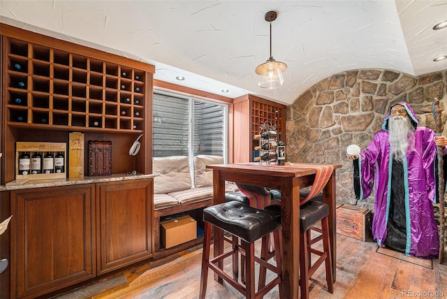 wine area featuring light wood-style floors and vaulted ceiling