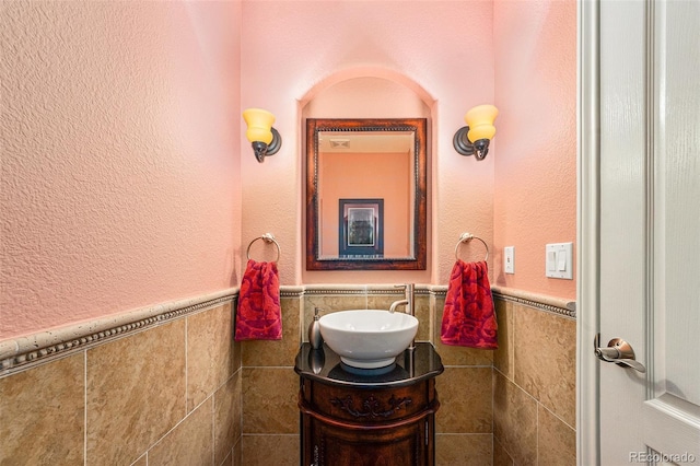 bathroom with wainscoting, tile walls, and vanity