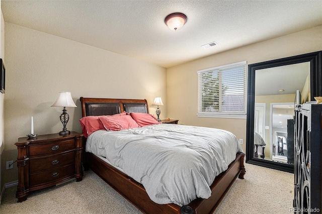 bedroom with light carpet, visible vents, and a textured ceiling