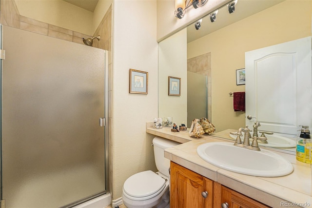 bathroom with vanity, a shower stall, and toilet