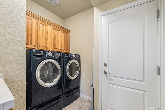 laundry area featuring visible vents, washer and clothes dryer, cabinet space, light tile patterned floors, and a textured wall