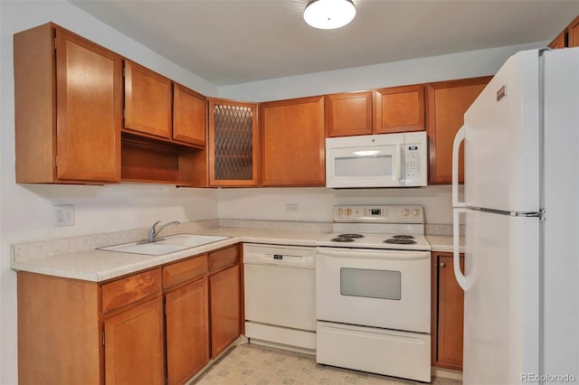 kitchen with light countertops, brown cabinets, a sink, and white appliances
