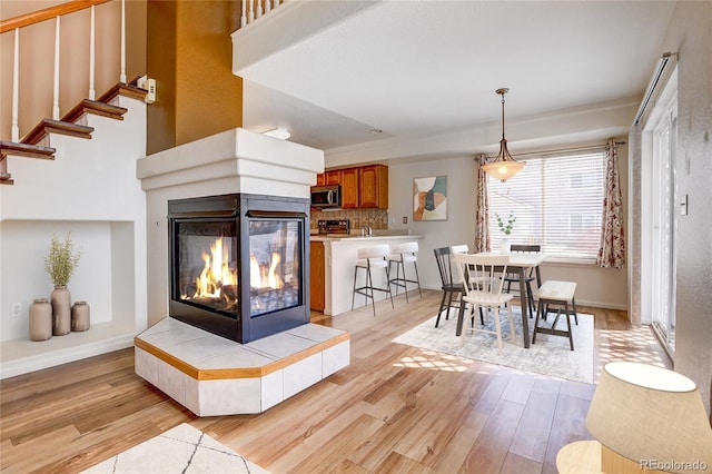 dining area featuring baseboards, light wood finished floors, and a tile fireplace