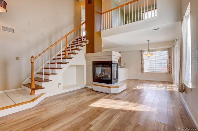 stairway featuring wood finished floors, visible vents, and a towering ceiling