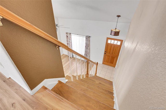 staircase with tile patterned flooring, ceiling fan, and a textured wall