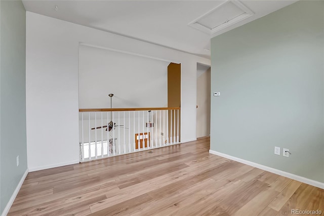 unfurnished room with baseboards, attic access, wood finished floors, and a ceiling fan