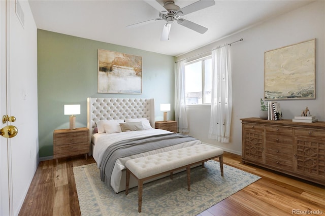 bedroom with a ceiling fan, wood finished floors, visible vents, and baseboards