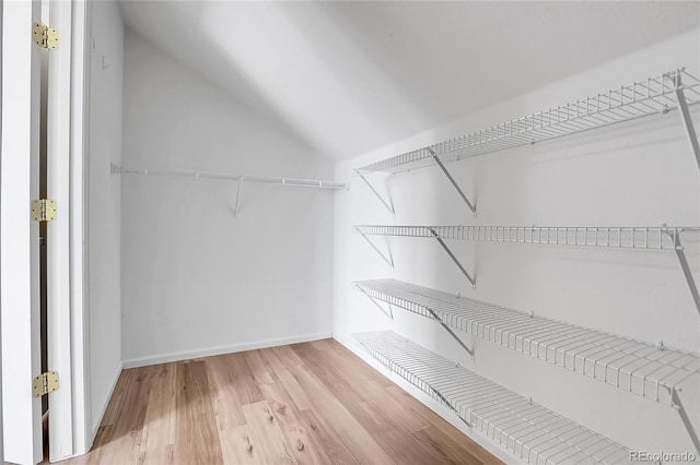 walk in closet with lofted ceiling and light wood-style floors