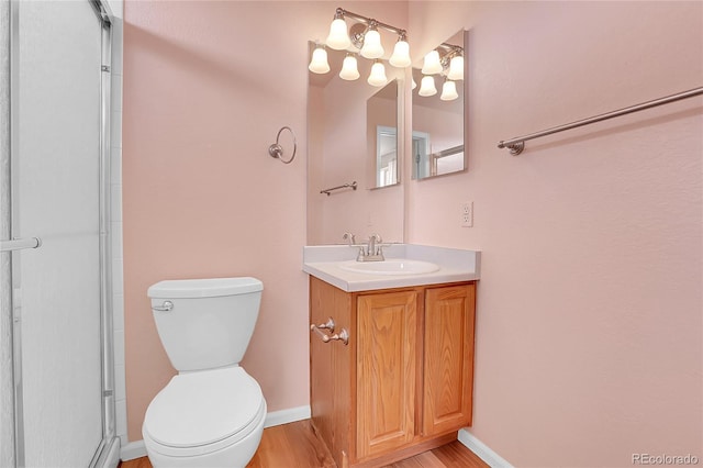 bathroom featuring baseboards, toilet, wood finished floors, and vanity