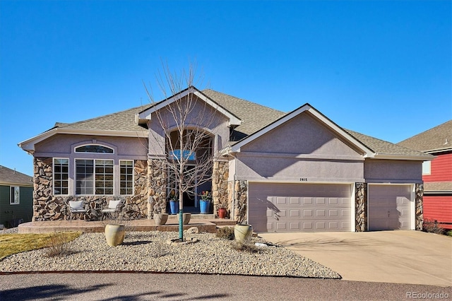 view of front facade with a garage, stone siding, and stucco siding