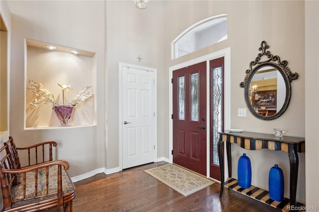 foyer with a high ceiling, baseboards, and wood finished floors