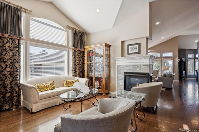 living room featuring recessed lighting, high vaulted ceiling, wood finished floors, and a stone fireplace