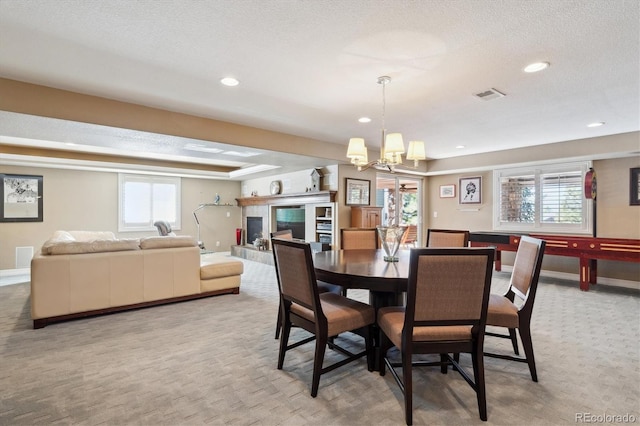 dining area with a textured ceiling, visible vents, a wealth of natural light, and light colored carpet