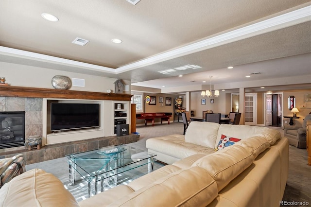 living area featuring a chandelier, recessed lighting, visible vents, a tiled fireplace, and a raised ceiling