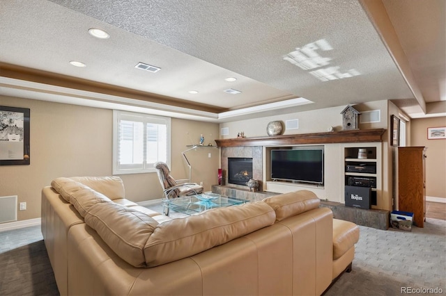 living area featuring a raised ceiling, visible vents, a textured ceiling, and baseboards