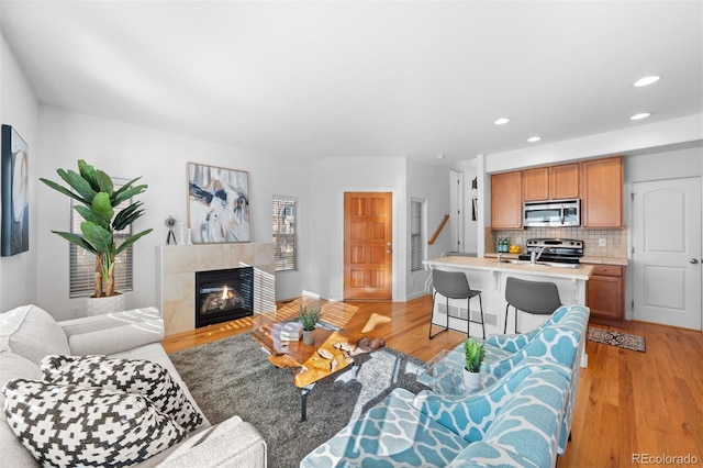 living room featuring light wood-type flooring and a tiled fireplace