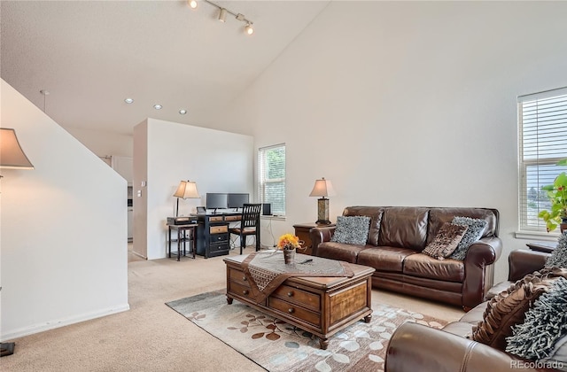 living room featuring high vaulted ceiling, light colored carpet, plenty of natural light, and baseboards