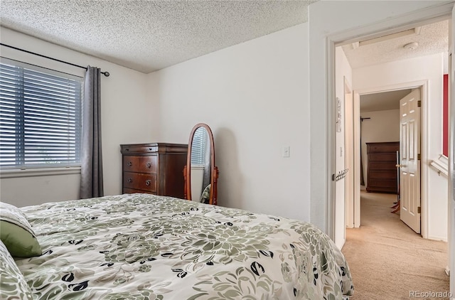 bedroom featuring light colored carpet and a textured ceiling