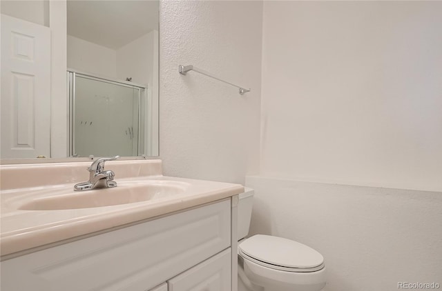 bathroom featuring vanity, a stall shower, toilet, and a textured wall