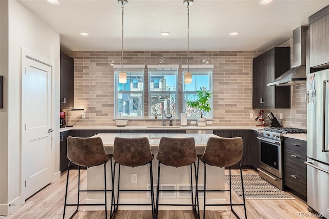 kitchen with decorative backsplash, wall chimney exhaust hood, stainless steel appliances, and light hardwood / wood-style floors